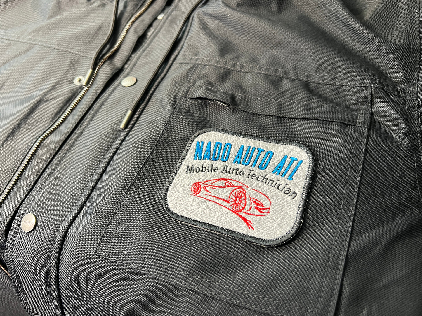 Patch on a jacket with custom auto company text and car illustration.